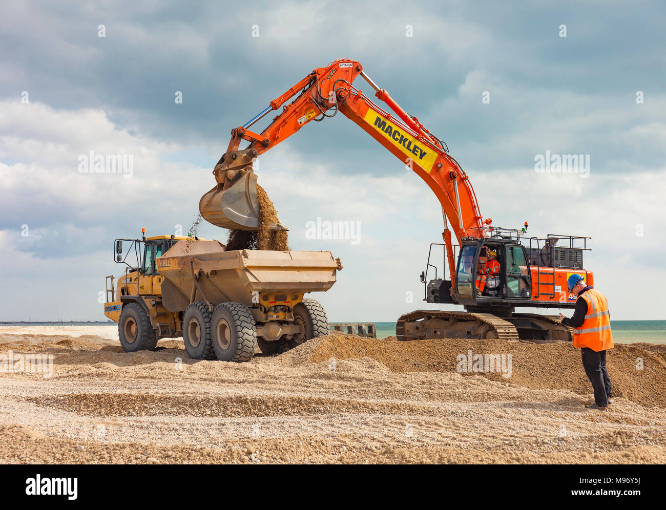 excavator-loading-a-dumper-truck-on-a-beach-M96Y5J.jpg